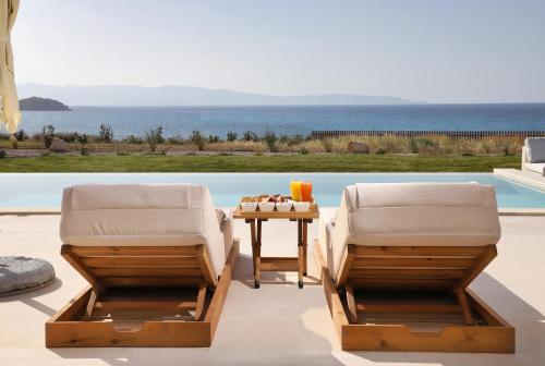 two chairs and a table next to a pool at OLIVIA'S Villas in Mochlos
