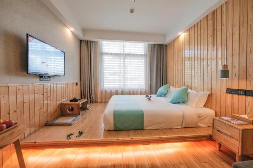 a bedroom with a large bed and a flat screen tv at Meadow Lodge Hotel Taizhou in Taizhou