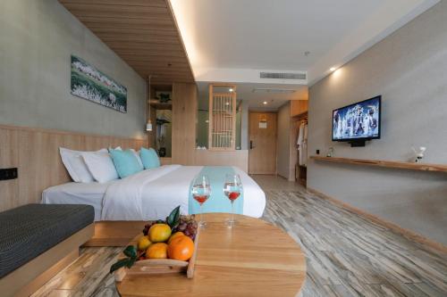 a hotel room with a bed and a table with wine glasses at Meadow Lodge Hotel Taizhou in Taizhou