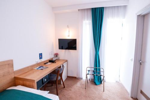 a bedroom with a desk and a bed and a window at Stil Hotel in Bucharest