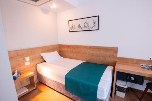 a small bedroom with a bed and a desk at Stil Hotel in Bucharest