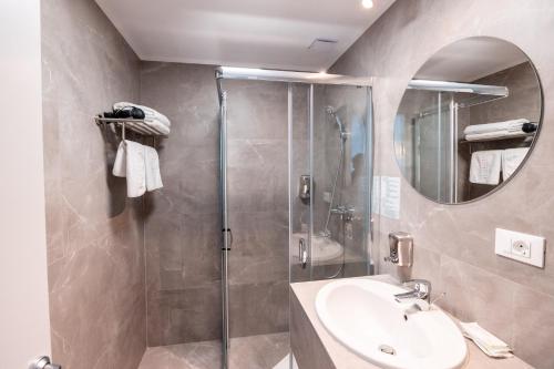 a bathroom with a shower and a sink and a mirror at Stil Hotel in Bucharest