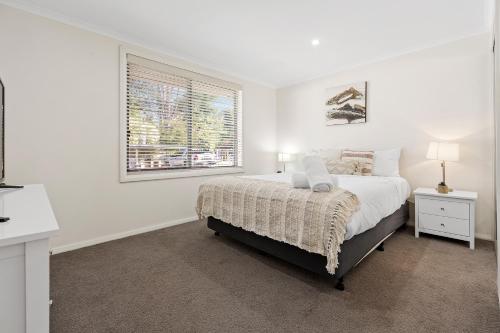 a white bedroom with a bed and a window at Tasman Holiday Parks - South Bright in Bright