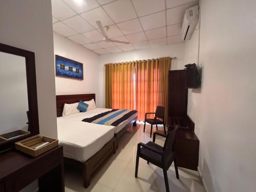 Schlafzimmer mit einem Bett, einem Schreibtisch und einem Fenster in der Unterkunft Bay Beach Hotel in Nilaveli
