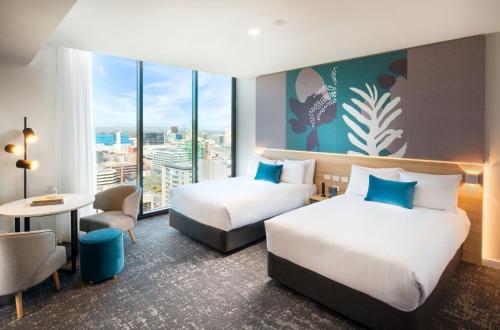 a hotel room with two beds and a table and chairs at Crowne Plaza Adelaide by IHG in Adelaide