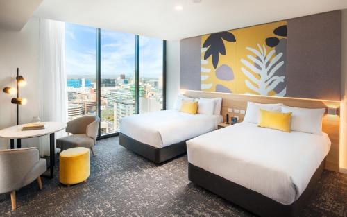 a hotel room with two beds and a desk at Crowne Plaza Adelaide by IHG in Adelaide