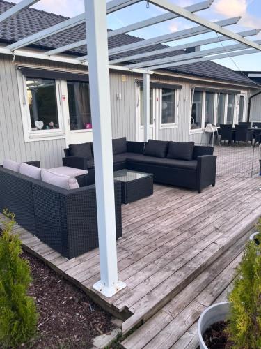 a patio with couches and a table on a deck at Villa, Barnvänlig, nära strand/shopping in Halmstad