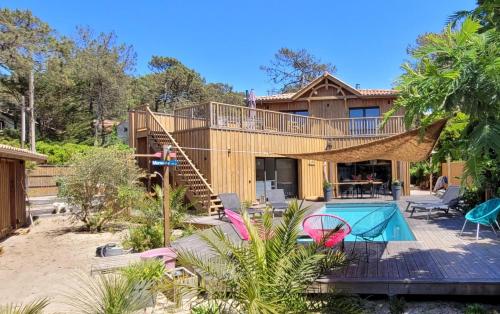 a house with a deck and a swimming pool at Côté plage in Lacanau