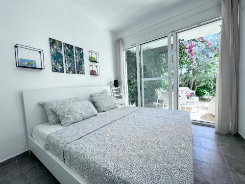 a white bedroom with a bed and a large window at Apartment Olive in Dhërmi