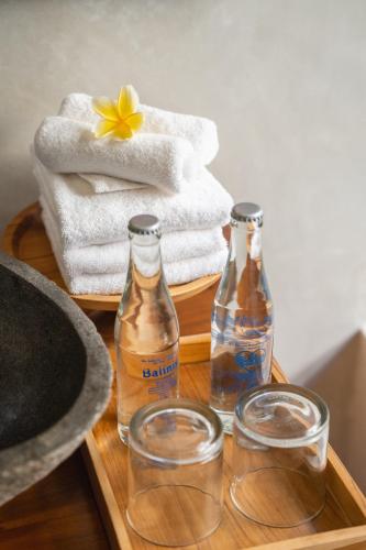 two bottles of water and glasses on a tray with towels at The Compass Rose Ubud in Ubud