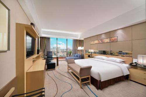 a hotel room with a large bed and a television at Dongguan Royal Garden Hotel in Dongguan
