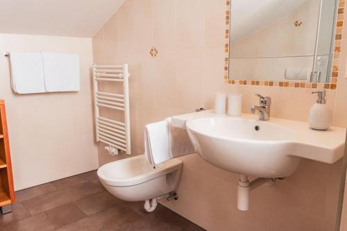 ein weißes Bad mit einem Waschbecken und einem WC in der Unterkunft Huberhof in Natz-Schabs