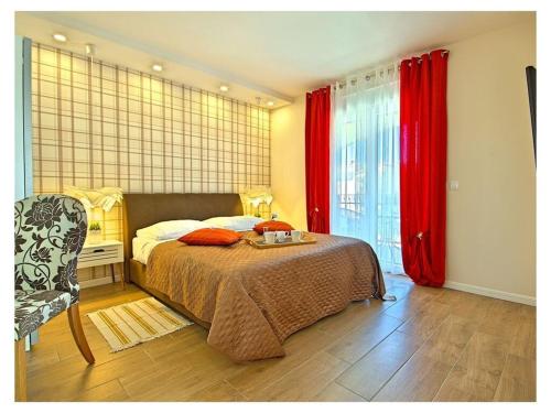 1 dormitorio con 1 cama con cortinas rojas y silla en Villa Luka Apartent Gray, en Funtana