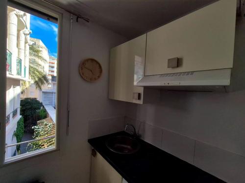 une cuisine avec un évier et une horloge murale dans l'établissement Studio plein centre de Juan - Proche plage et gare, à Antibes