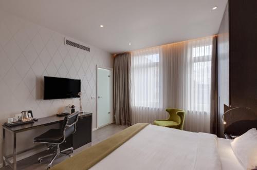 a hotel room with a bed and a desk and a television at Holiday Inn Dresden - Am Zwinger by IHG in Dresden