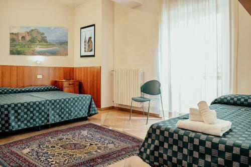 a hotel room with two beds and a chair at Nazareth Residence in Viterbo