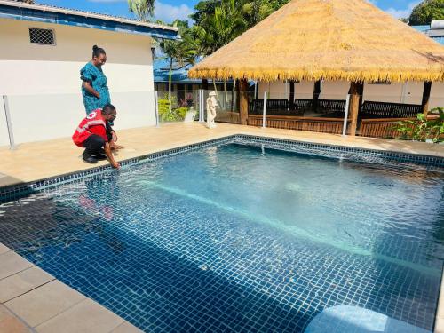 una donna e un bambino in piedi accanto alla piscina di Le Better Inn Hotel a Port Vila