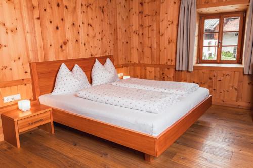 Schlafzimmer mit einem Bett mit Holzwänden und einem Fenster in der Unterkunft Huberhof in Natz-Schabs