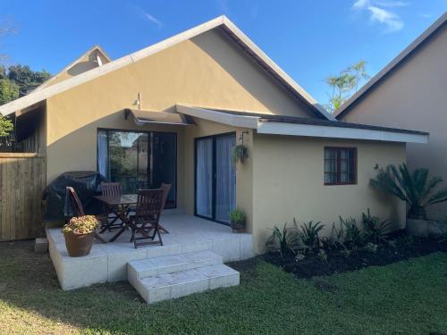 a small house with a patio with a table and chairs at PINE COTTAGE Self catering fully equipped 2 bedroom, Queen bed 3 singles 65sqm cosy private cottage in Durban