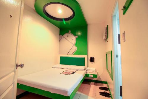 Habitación pequeña con cama con pared verde en Astrotel Calamba, en Calambá