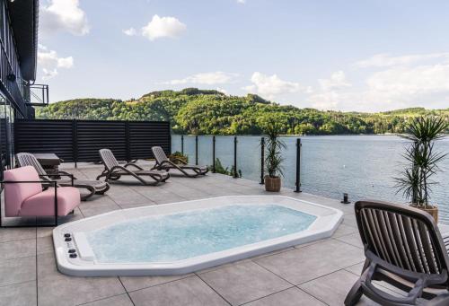 a hot tub on a patio next to a body of water at NOI Resort SPA - woda i las in Tęgoborze