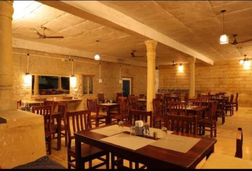a restaurant with wooden tables and chairs in a room at Royal Adventure Camp & Resort in Jaisalmer
