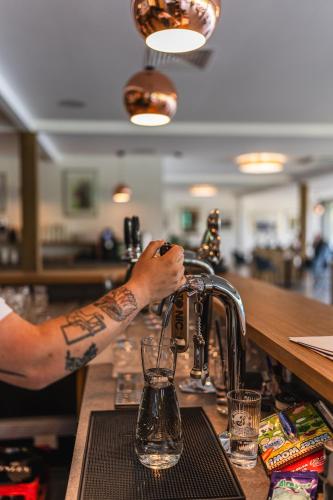 a man with a tattoo on his arm preparing a drink at a bar at NOI Resort SPA - woda i las in Tęgoborze