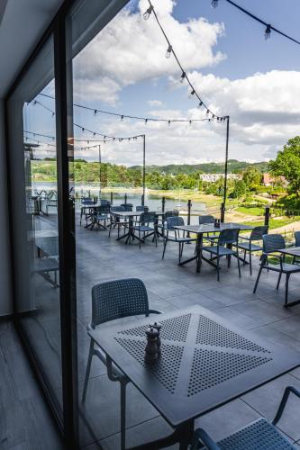 a patio with tables and chairs and a view of the water at NOI Resort SPA - woda i las in Tęgoborze