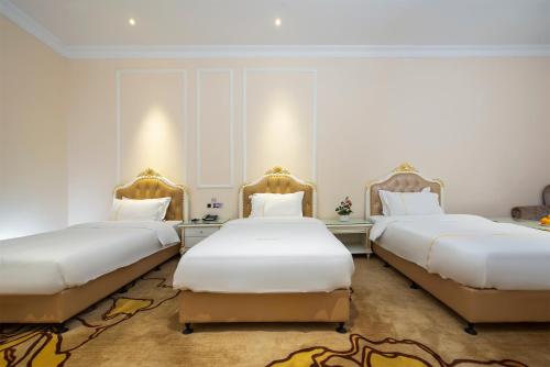 two beds in a room with white walls at Caribbean Hotel Zhongshan in Zhongshan