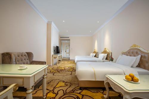 a hotel room with two beds and a table at Caribbean Hotel Zhongshan in Zhongshan
