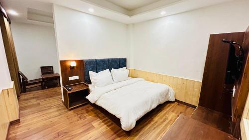 a bedroom with a white bed and a wooden floor at Hotel Ocean & Hotel Meadows Hill ! Rooftop Restaurant ! Near Hadimba Temple in Manāli