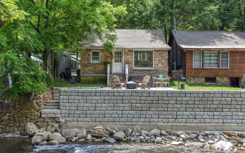 a house with a stone retaining wall next to a river at River Romance in Gatlinburg