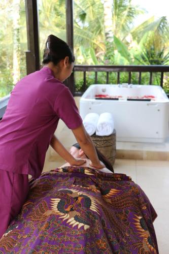 a woman in purple shirt ironing a bed at Nandini Jungle by Hanging Gardens in Payangan
