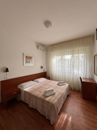 a bedroom with a bed and a desk and a window at Garnì Garten in Milano Marittima