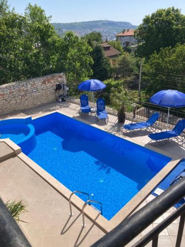 a swimming pool with two blue chairs and umbrellas at Panorama Pearl in Balchik