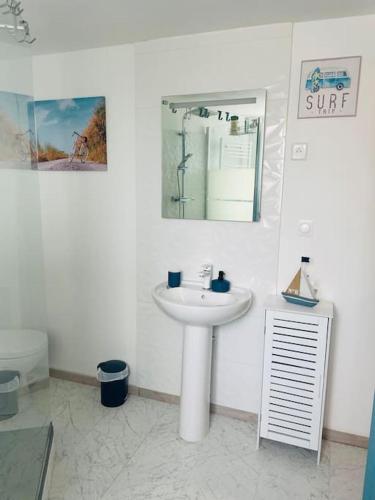une salle de bain blanche avec un lavabo et un miroir dans l'établissement Duplex Chez Caro, 180m de la mer à Cayeux sur mer, à Cayeux-sur-Mer