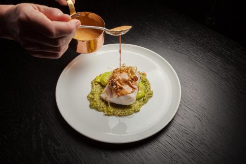 a person holding a plate of food on a table at Lyngen Experience Aurora Hut in Straumen