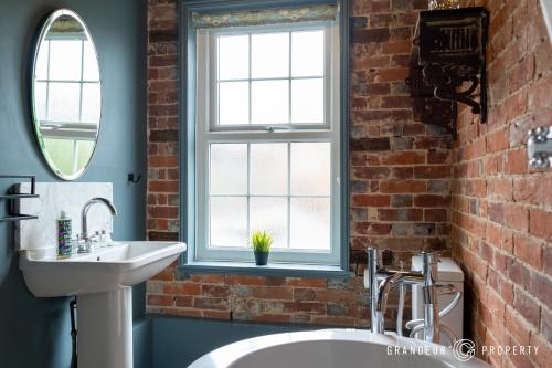 a bathroom with a white sink and a brick wall at The Blue House by Grandeur Property in Lymington