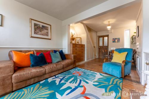 a living room with a brown couch and colorful pillows at The Blue House by Grandeur Property in Lymington