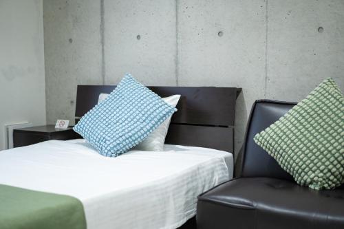 een bed met blauwe en witte kussens en een stoel bij Hotel Paradiso Miyakojima in Miyako Island