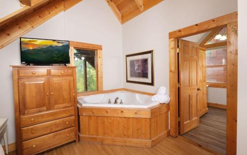 加特林堡的住宿－Gigis Getaway，带浴缸的浴室以及木柜上的电视。