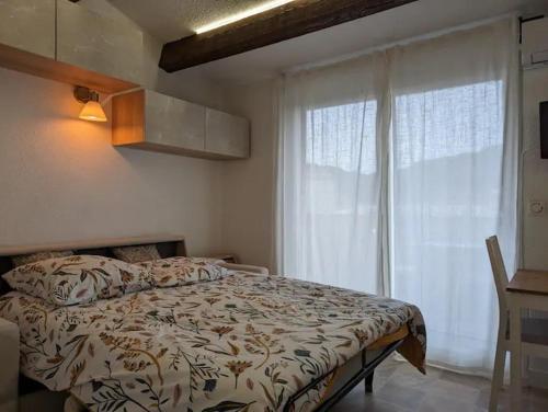 une chambre avec un lit et une grande fenêtre dans l'établissement Appartement Pinède Piscine Clim proche Plage village naturiste, au Cap d'Agde