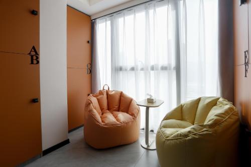 two chairs and a table in a room with a window at Yunbo Youth Hostel Ürümqi in Ürümqi