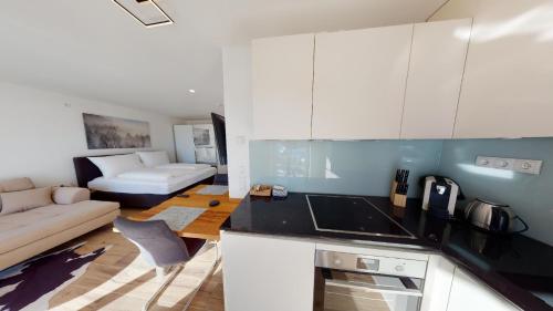 a kitchen with white cabinets and a living room with a couch at Downhill Lodge Tauplitz in Tauplitz