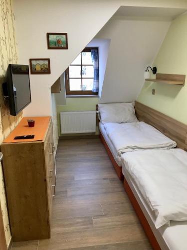 a room with two beds and a desk and a tv at Golden Wood Apartments in Plzeň