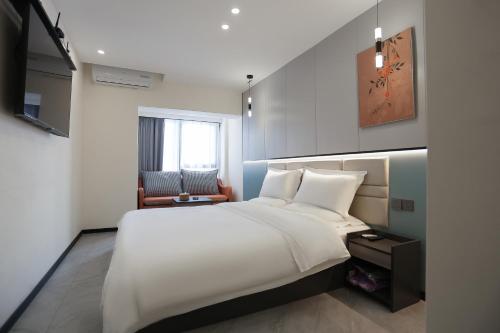 a bedroom with a large white bed and a chair at Yunbo Youth Hostel Ürümqi in Ürümqi