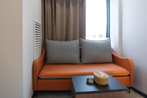 an orange couch in a room with a table at Yunbo Youth Hostel Ürümqi in Ürümqi