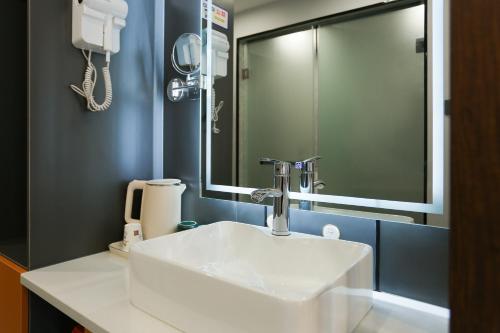 a bathroom with a white sink and a mirror at Yunbo Youth Hostel Ürümqi in Ürümqi