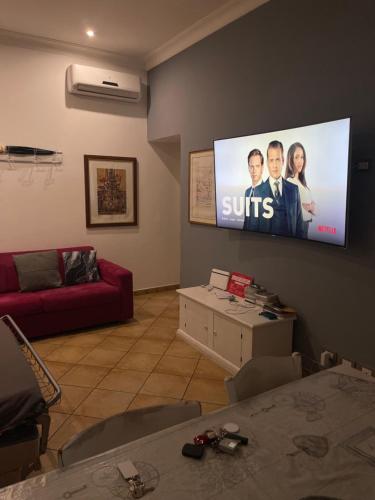ein Wohnzimmer mit einem Flachbild-TV an der Wand in der Unterkunft All Suite Colosseo in Rom