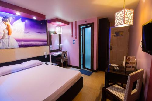 a bedroom with a bed and a desk and a tv at Hotel Dreamworld Las Pinas in Manila